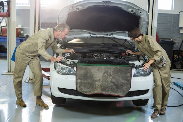 Two mechanics inspecting car engine bay