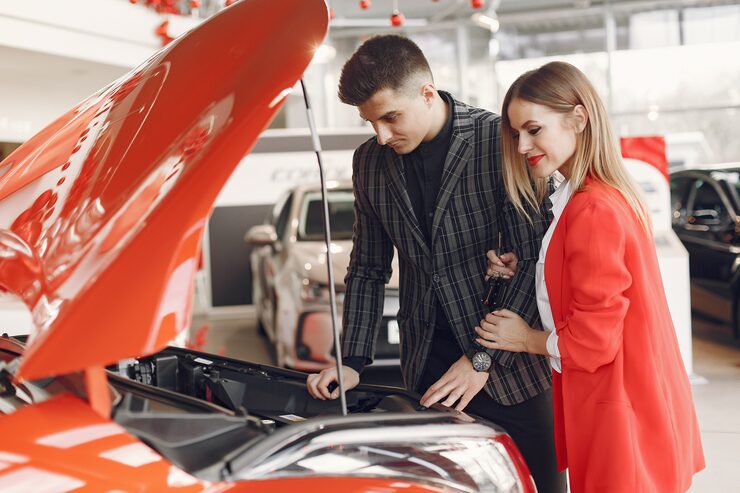 Couple examining engine at car showroom